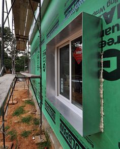 a green building under construction with scaffolding on the side and windows in place