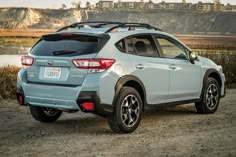 the rear end of a light blue subarunt parked on a dirt road