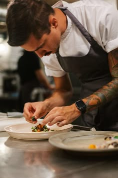 a man in an apron preparing food on top of a white plate with a knife and fork