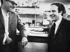 two men sitting at a table laughing and having drinks in front of the bar counter