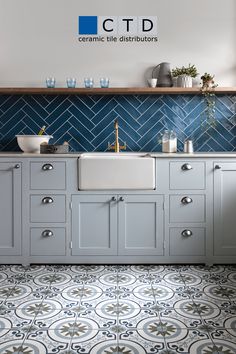 a kitchen with blue and white tiles on the floor, sink and countertop area