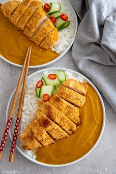 two plates filled with food and chopsticks next to each other