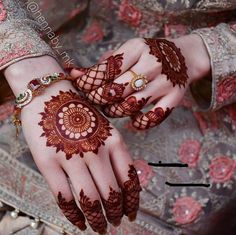 two hands with henna tattoos on them, one is holding the other's hand