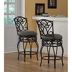 two black metal barstools with grey upholstered cushions in front of a fireplace