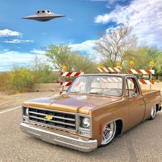 an old pickup truck parked on the side of the road in front of a flying object