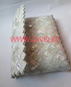 an origami pillow made out of newspaper paper with metal rivets on it