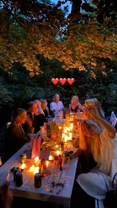 a group of people sitting around a table with candles in the shape of hearts on it