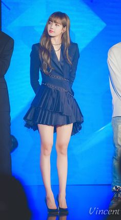 the girl is wearing a black dress and high heeled shoes while standing in front of a blue background