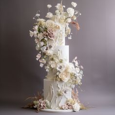 a three tiered white wedding cake with lots of flowers on the top and sides