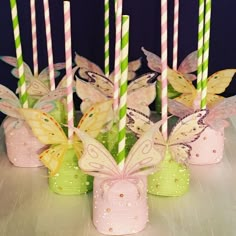 some pink and green vases with butterflies on them are sitting on a table in front of candles