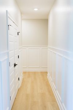 an empty room with white walls and wood floors is seen in this image from the hallway