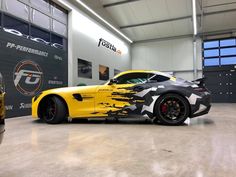 a yellow sports car with black flames on it's side in a garage area