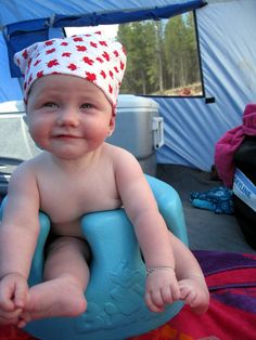 a baby sitting in a blue potty chair with a red and white hat on