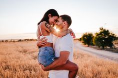 a man holding a woman in the middle of a field with sun shining through his eyes