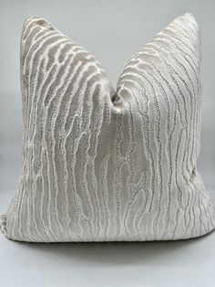 a white pillow with wavy lines on the front and back of it, sitting on a gray surface