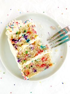 a slice of cake with white frosting and sprinkles on a plate