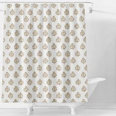 a shower curtain with an ornate design in gold on a white bathroom wall and floor