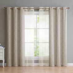 a living room with a white table and two curtains on the window sill, in front of a gray wall