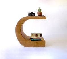 a wooden shelf with books and a camera on it, in front of a white wall