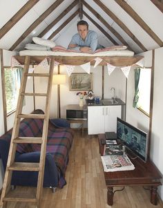 a man sitting on top of a bunk bed in a room with wood flooring