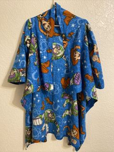 a blue shirt with cartoon characters on it hanging from a hook in a wall next to a white wall