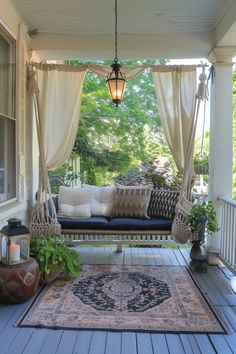 a porch with a bench, rug and lamp on the front porch area that is covered in white drapes