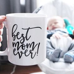 a person holding a coffee mug with the words'best mom ever'on it