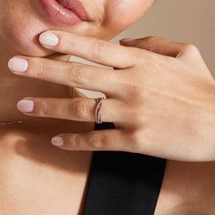 a close up of a person wearing a ring on their finger and holding her hand near her face