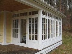 a small yellow house in the woods with lots of windows on it's side