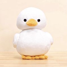 a white stuffed duck sitting on top of a wooden table