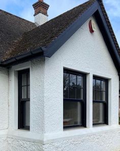 a white house with two windows and a black roof