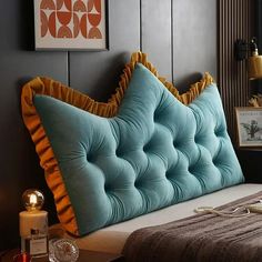 a bed with blue and yellow pillows in a dark colored room next to a window