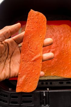 a person holding a piece of food in their left hand while cooking something on the grill