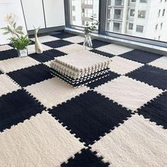 a black and white checkered rug in the middle of a room with large windows