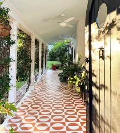 an outdoor walkway with potted plants on either side and a ceiling fan hanging from the ceiling