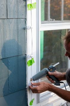 a man is using a power drill to paint the side of a house