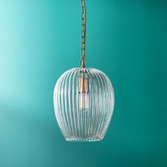 a glass light hanging from a chain on a blue wall with a green back ground