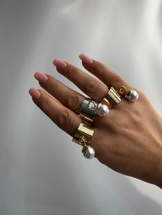 a woman's hand with two rings and pearls on it, both in gold and silver