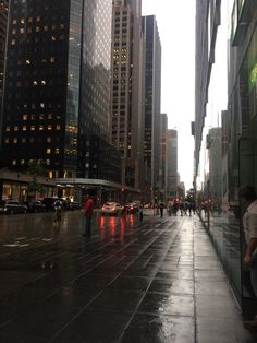 people are walking down the street in the rain