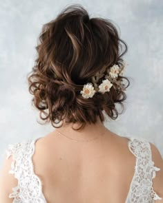 the back of a woman's head with flowers in her hair, wearing a white dress