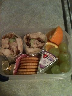 a plastic container filled with fruit and crackers on top of a marble countertop