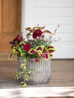 a vase filled with lots of flowers on top of a wooden floor next to a door