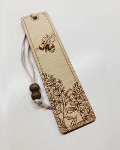 a wooden bookmark with an image of a bee and flowers on it, hanging from a string