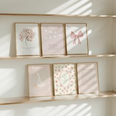 three wooden shelves holding greeting cards and two framed pictures on top of each shelf are decorated with pink flowers