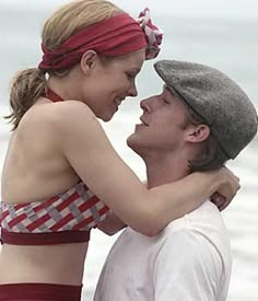 a man and woman standing next to each other on the beach