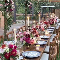 a long table set up with flowers and candles for an outdoor wedding reception in the backyard