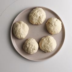 four uncooked doughnuts sitting on a plate