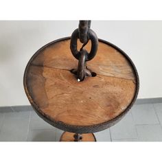 an old wooden table with metal chains on the top and bottom, sitting on tile flooring