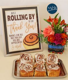 there are some cinnamon rolls on a tray next to a sign that says, just rolling by thank you