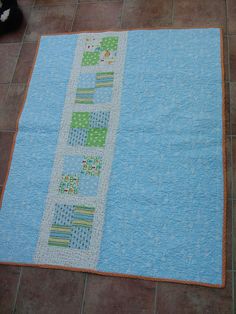 a blue and green quilt sitting on top of a tile floor